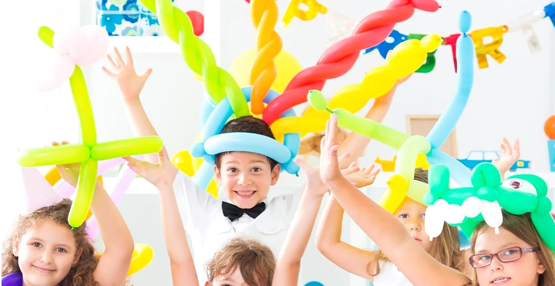 Kids at a party with twisted balloon hats.