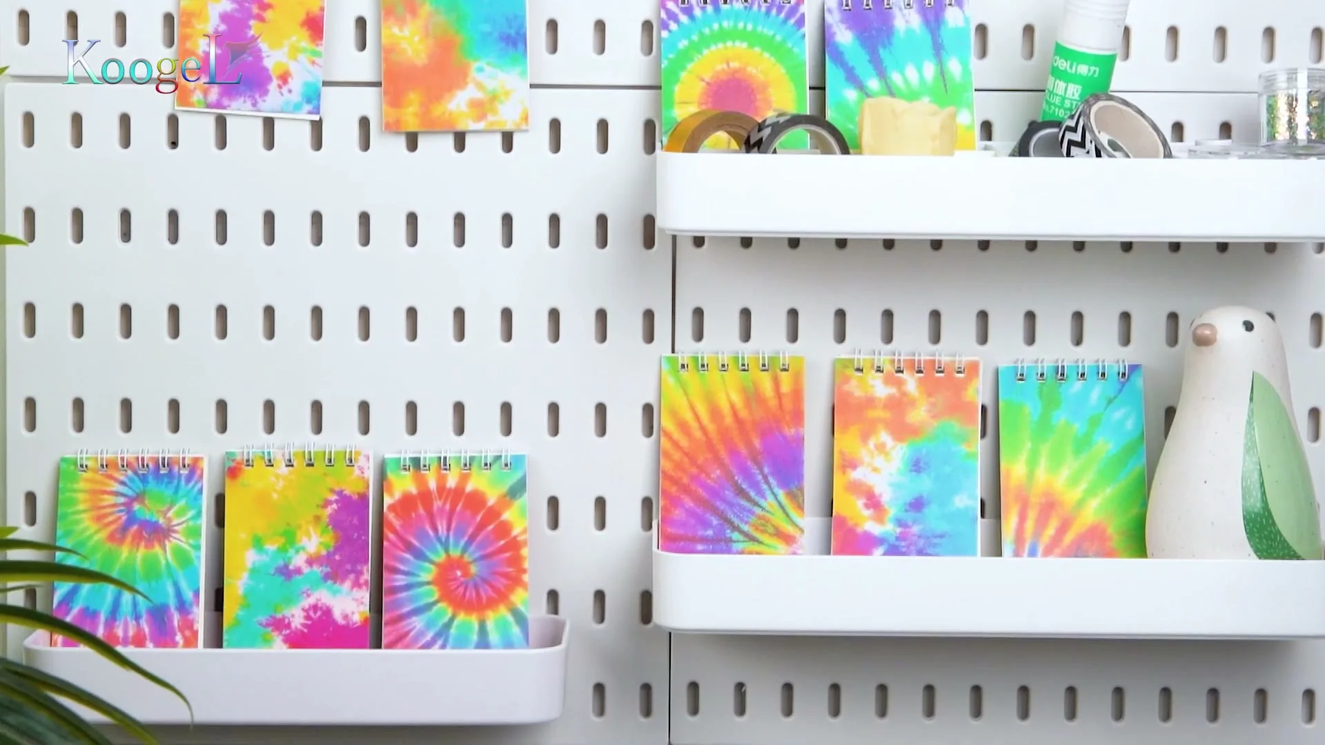 Tie-dye Koogel pocket notebooks on a pegboard shelf.